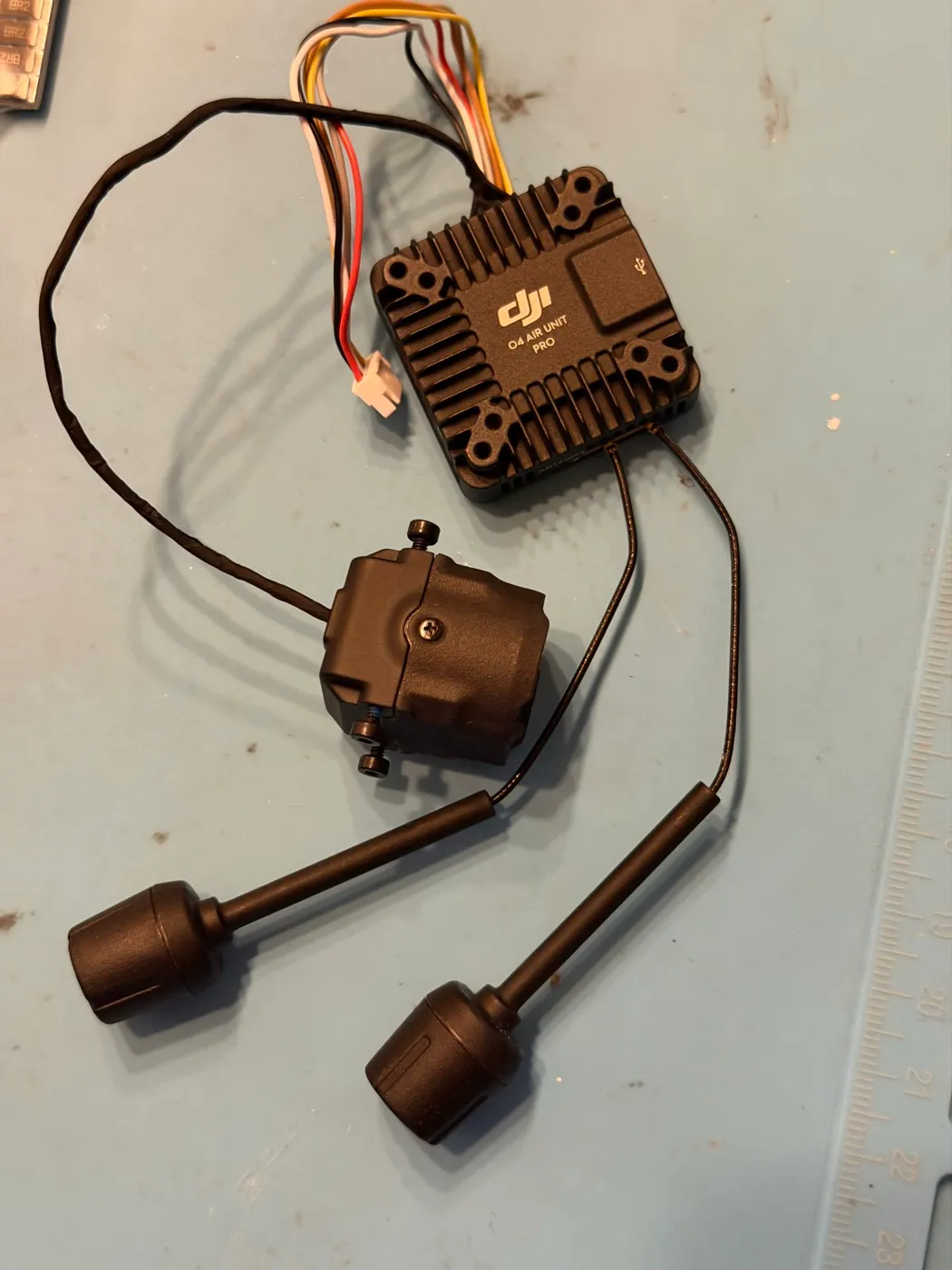 The DJI O4 Air Unit Pro from this build: the finned air unit body with its camera attached by the ribbon coax, both stock antennas connected, and the 6-pin harness